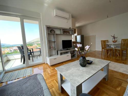 Una sala de estar con una mesa y un televisor. en Apartman Sunny Day, en Trebinje