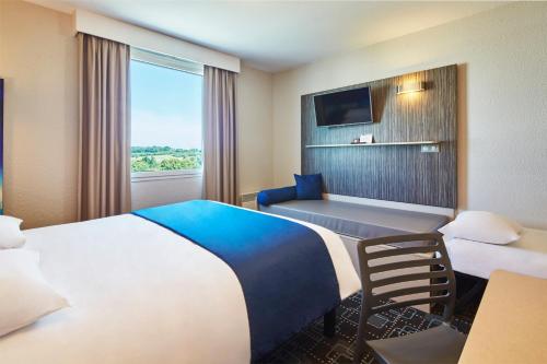 a hotel room with two beds and a television at Kyriad Poitiers Jules Verne Site du Futuroscope in Chasseneuil-du-Poitou