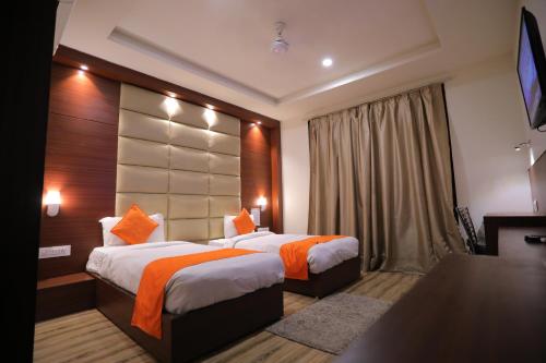 um quarto de hotel com duas camas e uma televisão em Hotel Marygold em Agra