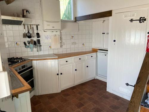 a kitchen with white cabinets and white appliances at Dolphin Cottage Lyme Regis in Lyme Regis