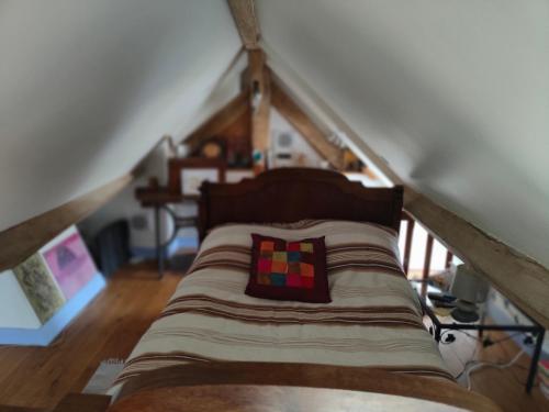 - un lit mansardé avec un oreiller dans l'établissement La Maison Bleue de Husseau Ancienne ferme semi-troglodytique 18e siècle, à Montlouis-sur-Loire