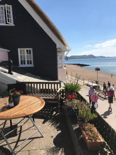 a black house with a wooden table and a beach at Dolphin Cottage Lyme Regis in Lyme Regis
