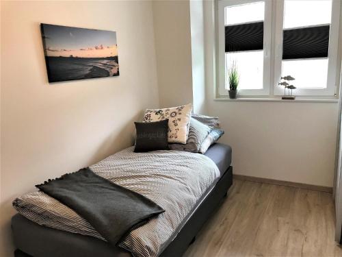 a bed in a room with two windows at Auszeit-Kenkel in Hohwacht