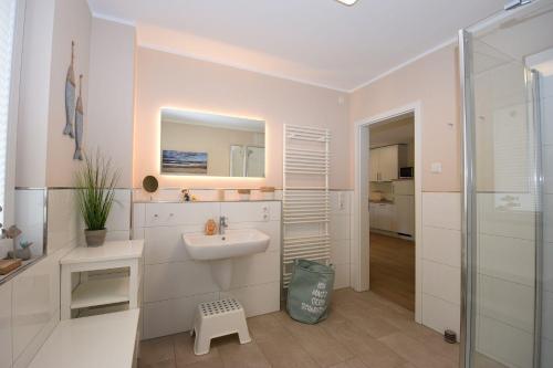 a white bathroom with a sink and a mirror at Auszeit-Kenkel in Hohwacht