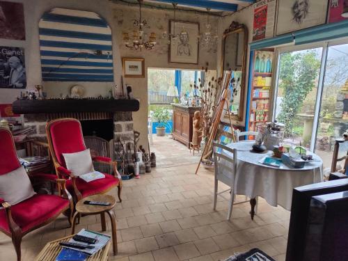 a room with a table and chairs and a fireplace at La Maison Bleue de Husseau Ancienne ferme semi-troglodytique 18e siècle in Montlouis-sur-Loire
