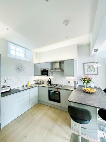 a kitchen with white cabinets and a counter top at Modern & Spacious 1 Bed Apt, West End in Edinburgh