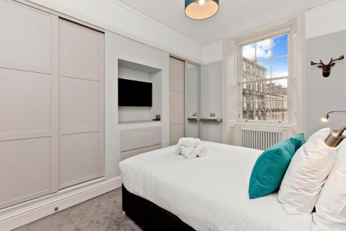 a white bedroom with a bed and a window at Modern & Spacious 1 Bed Apt, West End in Edinburgh