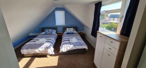 2 camas en una habitación con paredes azules y ventana en Parterre Holiday Apartments, en Sandown