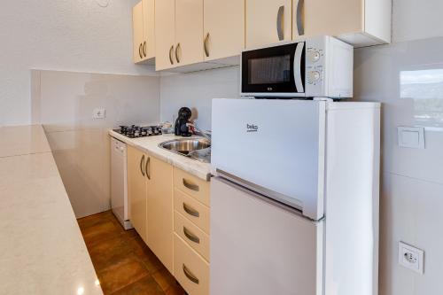 a kitchen with a white refrigerator and a sink at Apartments Habek in Vrboska