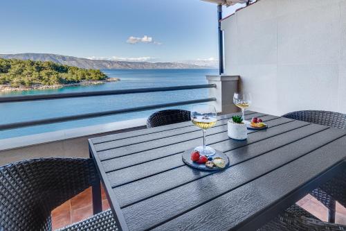 a table with two glasses of wine on a balcony at Apartments Habek in Vrboska