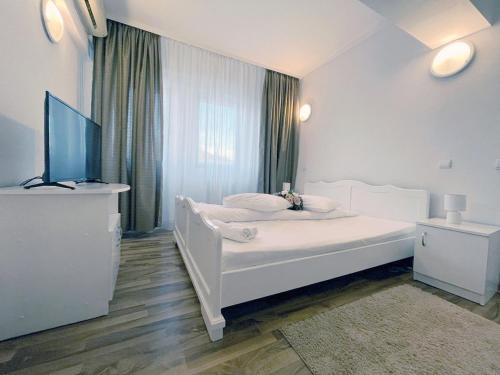 a white bedroom with a white bed and a window at Hotel Green House in Craiova