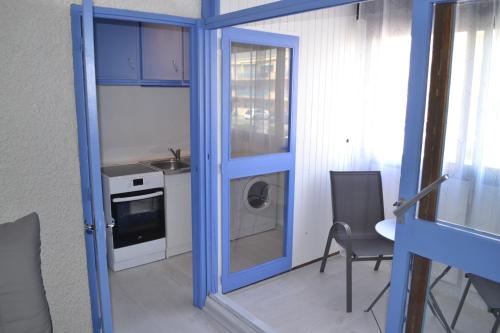 une cuisine avec une porte bleue, une table et des chaises dans l'établissement Résidence Palma proche plage et commerces, à Port-la-Nouvelle