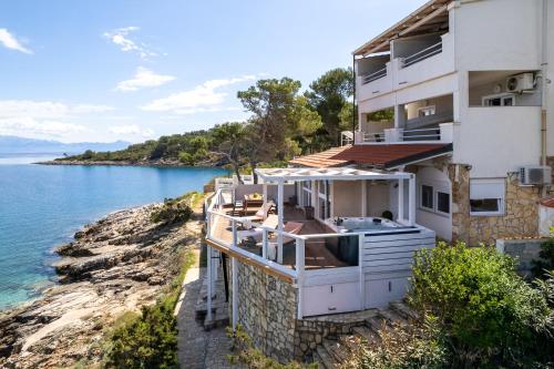 a house on a cliff next to the water at Apartments Habek in Vrboska