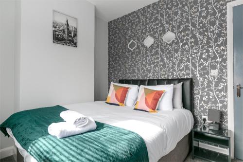 a bedroom with a bed with a green and white blanket at Modern & Contractors & Families & Spacious & Private Parking in Derby