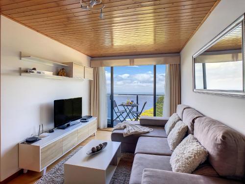 a living room with a couch and a flat screen tv at Casa Leão de Ouro by LovelyStay in São Jorge
