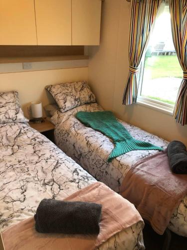 a bedroom with two beds and a window at Flosh Caravan, Manor House Park in Mawbray