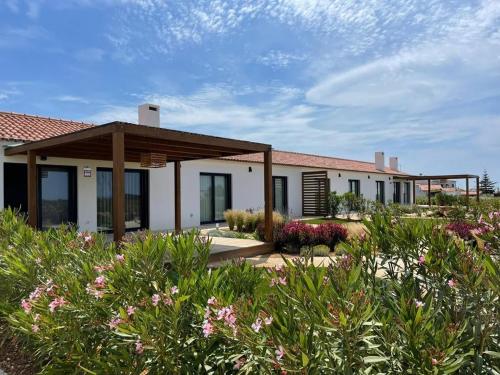 una casa con un jardín con flores delante en Quinta do Planalto Vicentino - Casas de Campo, en Aljezur