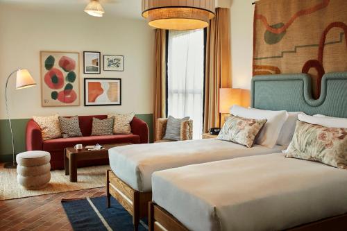 a hotel room with two beds and a couch at The Hoxton, Poblenou in Barcelona