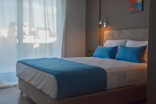 a bedroom with a bed with blue pillows and a window at Thisean Modern Suites By Athens Stay in Athens