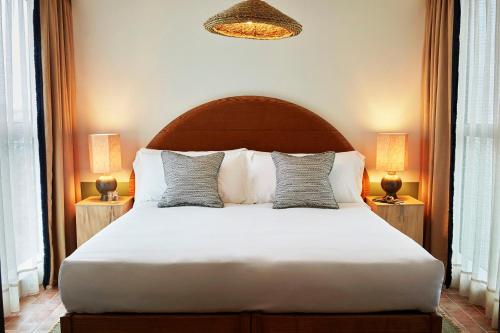 a bedroom with a large white bed with two lamps at The Hoxton, Poblenou in Barcelona