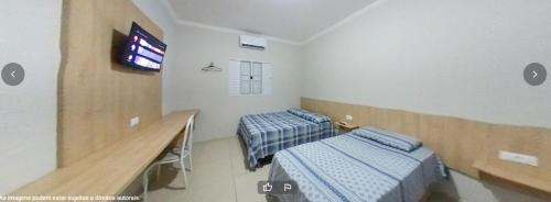 um quarto de hospital com duas camas e uma televisão em Hotel Platina em Santo Antônio da Platina