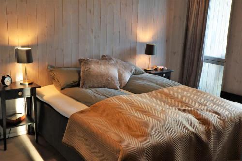 a bedroom with a bed with two lamps and two tables at Cozy Apartment by the slopes in Kvitfjell Vest in Favang