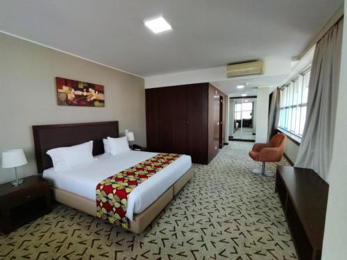 a hotel room with a bed and a chair at Skyna Hotel Luanda in Luanda