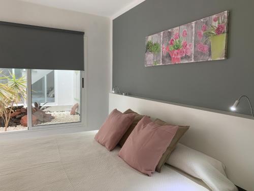 ein Schlafzimmer mit einem Bett mit rosa Kissen und einem Fenster in der Unterkunft Vivienda Tauro in Puerto del Carmen