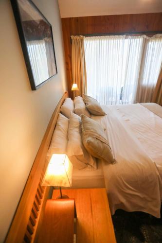 a large bed in a bedroom with a window at Arrayan Lake View Mountain Lodge & Casa De Te Arrayan in San Martín de los Andes