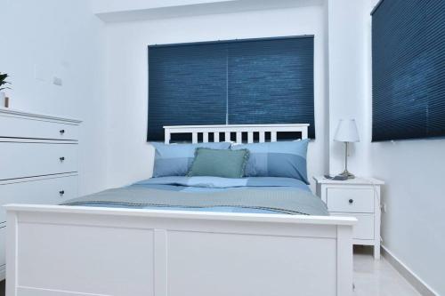 a white bedroom with a bed with blue pillows at Apto Juan Dolio Tepuy 601 F in Juan Pedro