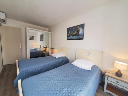 een slaapkamer met 2 bedden en een spiegel bij CAP HERMES 3 Pieces Climatise 6 Personnes in Fréjus