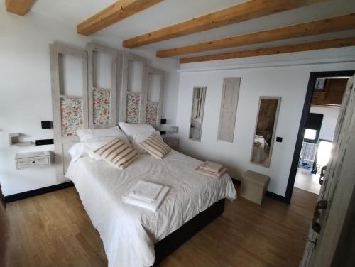 a bedroom with a large bed with white sheets at Casiña da Madalena in Ribadavia