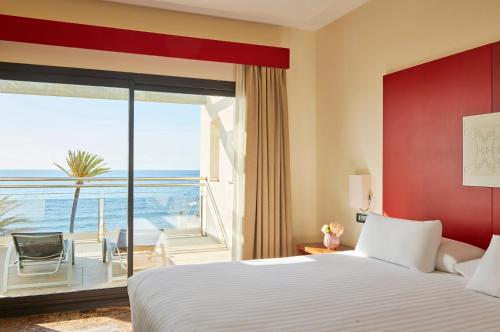 um quarto de hotel com uma cama e uma grande janela em Estepona Hotel & Spa Resort em Estepona