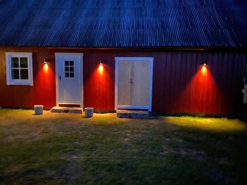 um edifício vermelho com duas portas brancas e luzes em Skog Fegen nära Ullared em Fegen