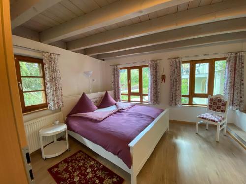 1 Schlafzimmer mit einem Bett mit lila Laken und Fenstern in der Unterkunft Kleines Haus Silberdistel in Todtmoos