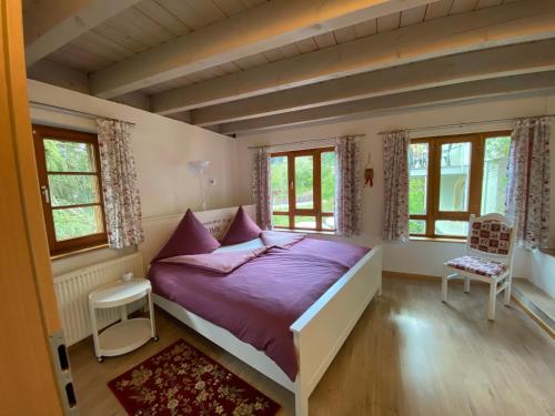 a bedroom with a bed with purple sheets and windows at Kleines Haus Silberdistel in Todtmoos