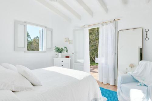 a white bedroom with a white bed and a window at Ca Aquamarine -Luxurious villa, walking distance from Saona Beach in Cala Saona