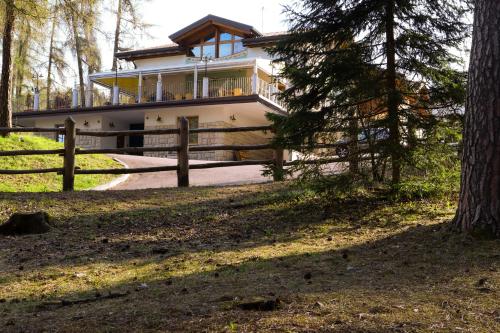 una casa con una valla delante de ella en hotel Parco Pineta en Cavareno