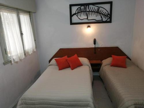 two beds with red pillows in a room at Suite Confortable en Palermo Omega in Buenos Aires