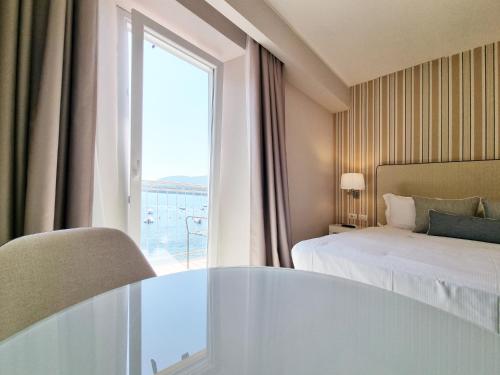 a hotel room with a bed and a large window at Hotel Plaza in Porto Azzurro