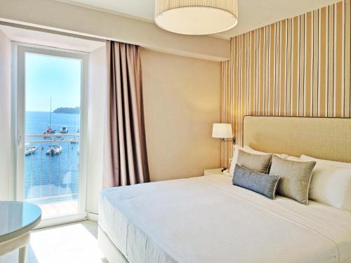 a hotel room with a bed and a large window at Hotel Plaza in Porto Azzurro