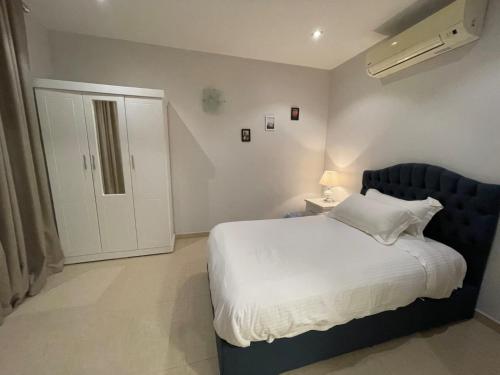 a bedroom with a white bed with a blue headboard at سافانا امواج Amwaj savana in Half Moon Bay