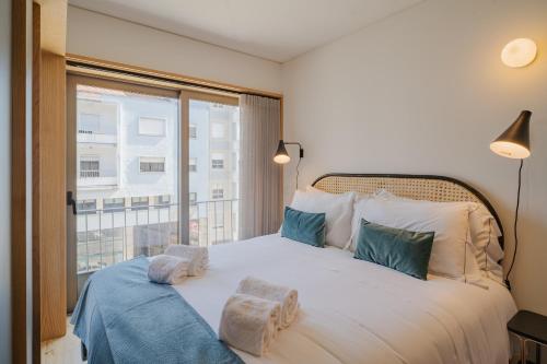 ein Schlafzimmer mit einem großen weißen Bett mit einem Fenster in der Unterkunft Feel Porto Corporate Housing Campanhã in Porto