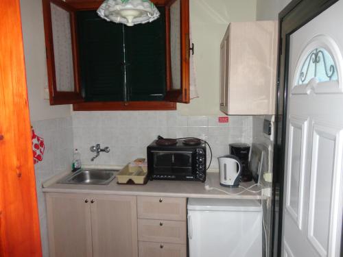 a small kitchen with a sink and a microwave at Stamatela Studios in Paleokastritsa
