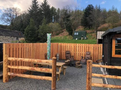 une clôture en bois avec une table et des chaises en bois dans l'établissement 1 Bed Cabin in the Magical Galloway Forest Park, à Newton Stewart