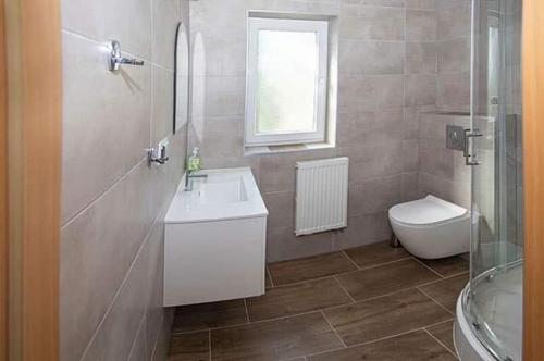 baño con lavabo y aseo y ventana en Ranczo nad Stawem en Ryn