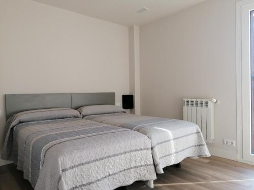 two beds in a bedroom with white walls at Casa Patxikuzuria in Espinal-Auzperri