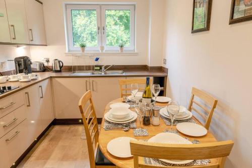 a kitchen with a wooden table and chairs in a kitchen at Hedgefield House - Serene Top Floor Flat in Inverness