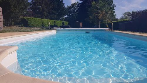 ein großer Pool mit blauem Wasser im Hof in der Unterkunft Les Cormiers in Cangey