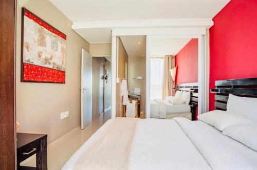 1 dormitorio con cama blanca y pared roja en Sea&Mountain view by Caline VIP en Ciudad del Cabo
